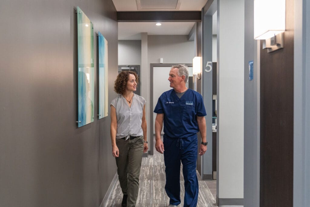 Dr. Bryan Simone walking with patient in dental office hallway during consultation