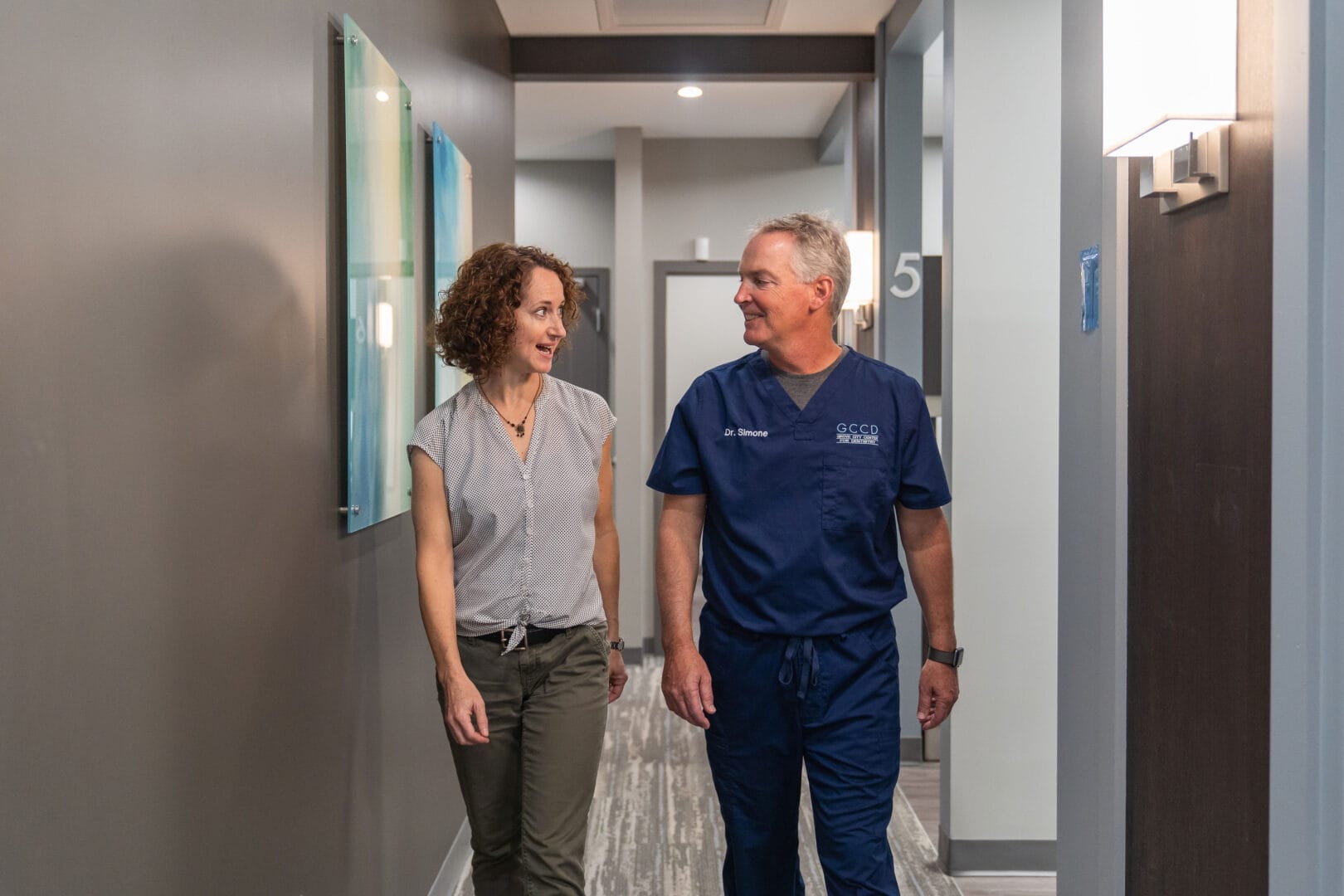 Dr Bryan Simone walking with patient in dental hallway