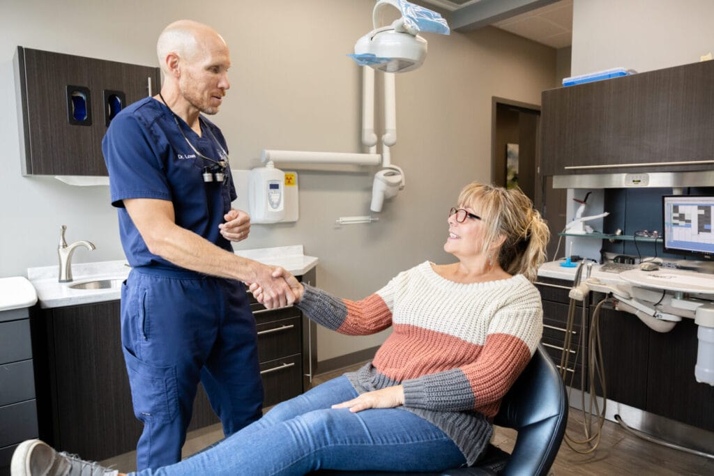 Dr Kyle Lowe shaking hands with patient in dental chair